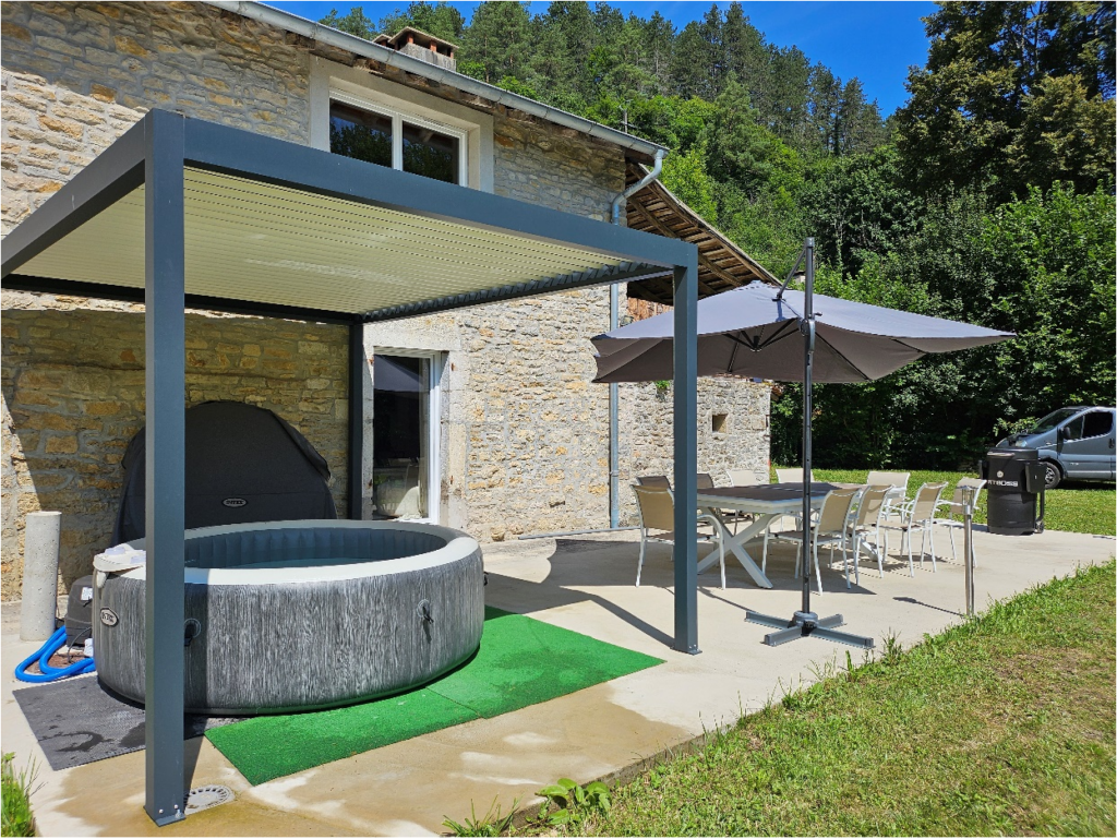 photo de la terrasse avec le jacuzzi et la table de jardin avec parasol déporté